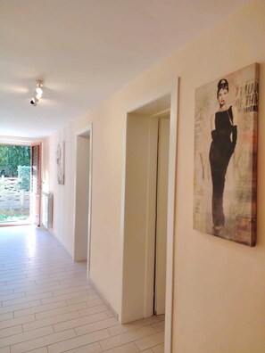 Ein Flur mit Fliesenboden, einer Tür und einem Poster an der Wand.