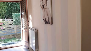 A hallway with a radiator, a door leading outside, and a wall with a framed picture. - Casa Vacanze Audrey - Porto Azzurro (Porto Azzurro)