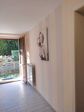 Ein Korridor mit Heizkörper, einer zur Außenseite führenden Tür und einer Wand mit einem gerahmten Bild.