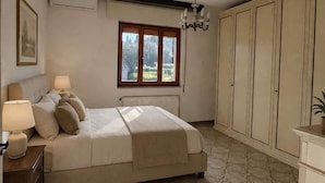 A bedroom with a bed, bedside lamps, a window, a radiator, and a chandelier. - Casa Vacanze Audrey - Porto Azzurro (Porto Azzurro)
