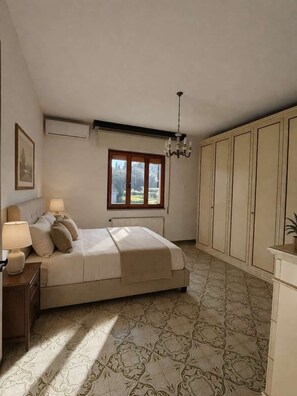 Ein Schlafzimmer mit Bett, Nachttischlampen, einem Fenster, einer Heizung und einer Chandelier.