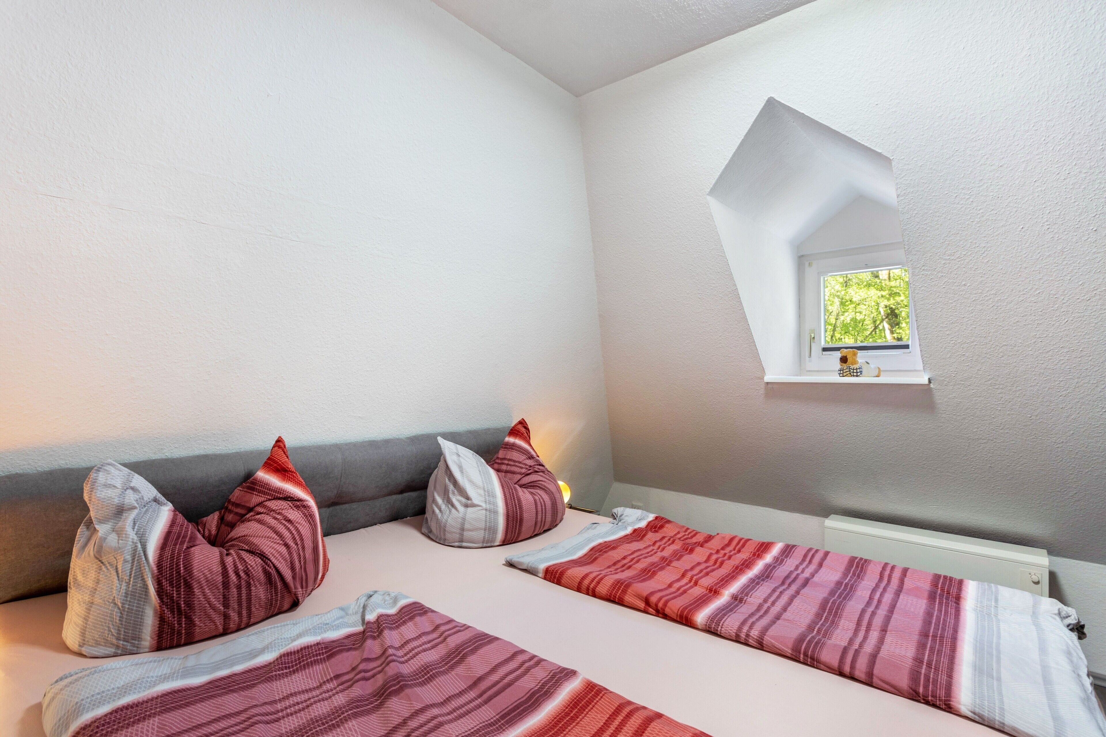 Een slaapkamer met twee bedden, een dakraam en een klein raam.