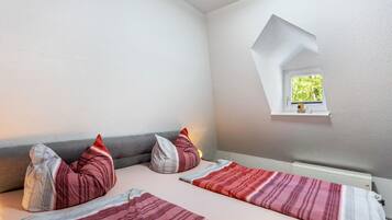 Een slaapkamer met twee bedden, een dakraam en een klein raam.