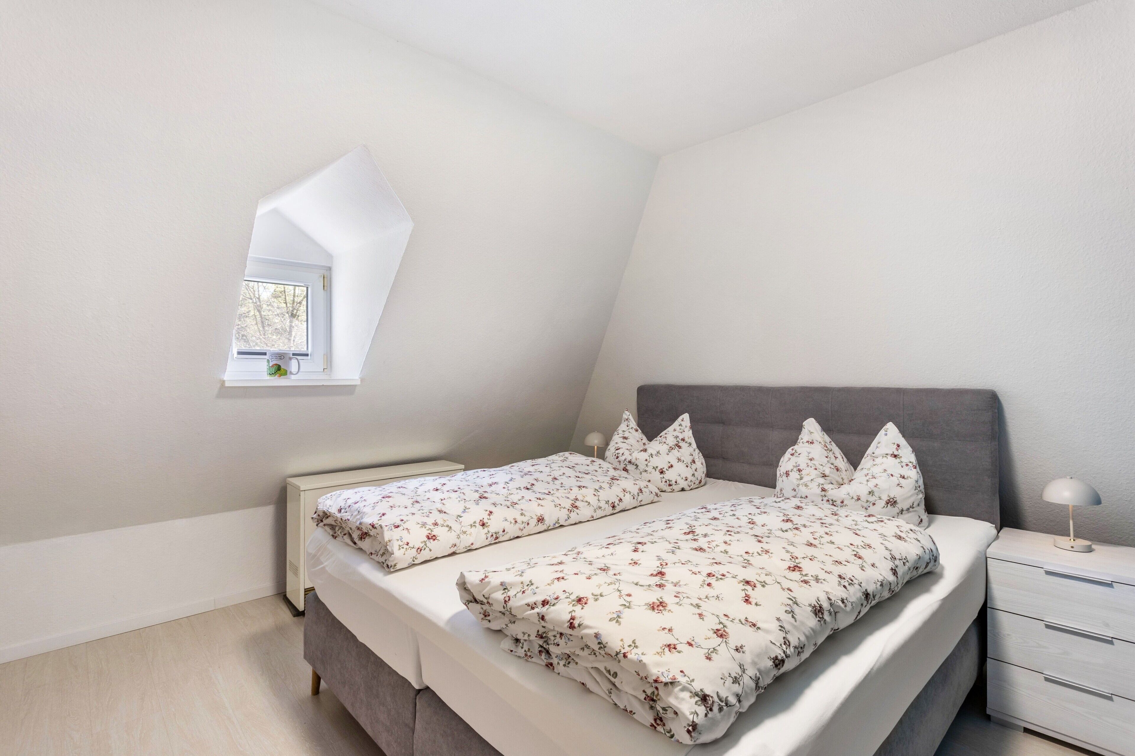Ein Schlafzimmer mit Bett, Nachttisch und Fenster.