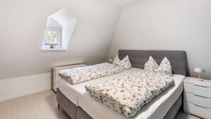 A bedroom with a bed, bedside table, and a window.