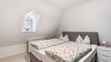 Ein Schlafzimmer mit Bett, Nachttisch und Fenster.