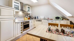 A kitchen with white cabinets, a wooden table, and a microwave.