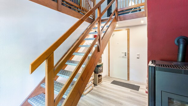 A wooden staircase with a patterned carpet, a door, and a wood-burning stove.