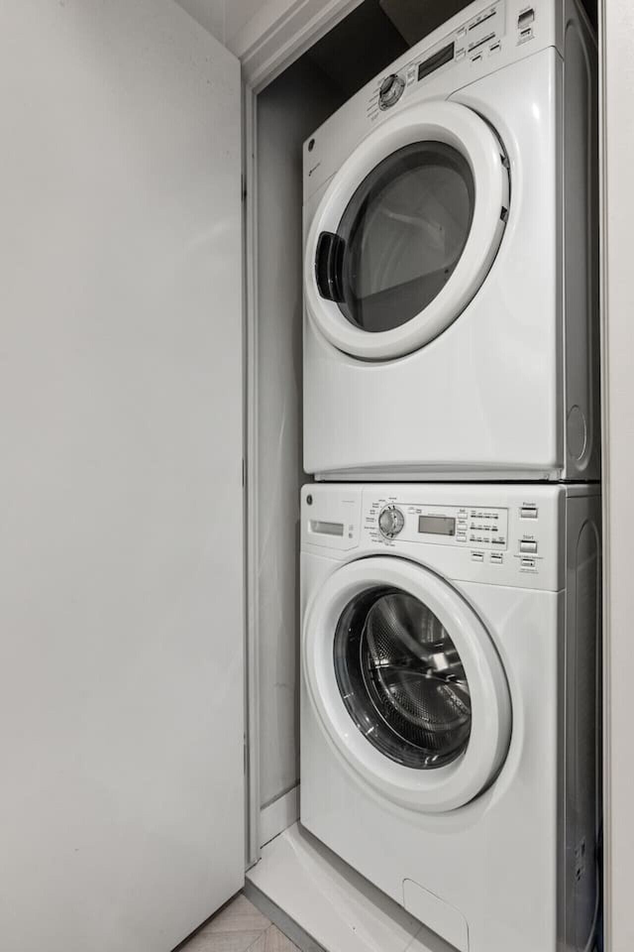 Eine übereinander gestellte Waschmaschine und Trockner in einer Ecke des Raumes.