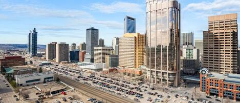 A cityscape with modern high-rise buildings, a parking lot, and a railway track.