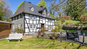 A traditional half-timbered house with a garden, a bench, and outdoor seating. - Apartment Kleine Auszeit with Mountain View in Historic Forester’s House (Olsberg)
