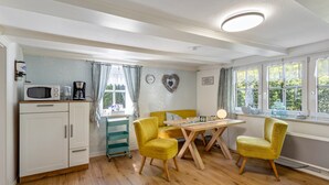 A kitchen with a microwave, coffee maker, and a dining table with chairs. - Apartment Kleine Auszeit with Mountain View in Historic Forester’s House (Olsberg)