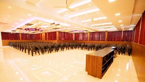Un salón de conferencias con hileras de sillas, un atril y un ventilador de techo.