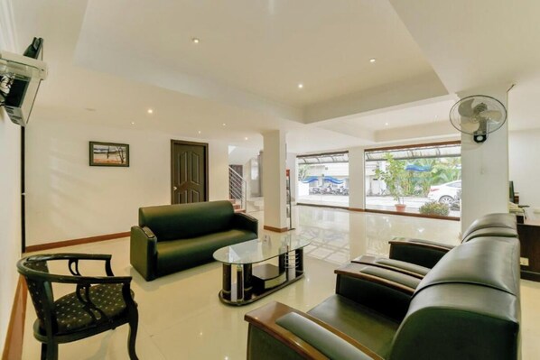 A modern hotel lobby with a glass coffee table, leather sofas, a black chair, and a large window with a view of parked cars and greenery outside. - Hotel Centree Point (Ernakulam)