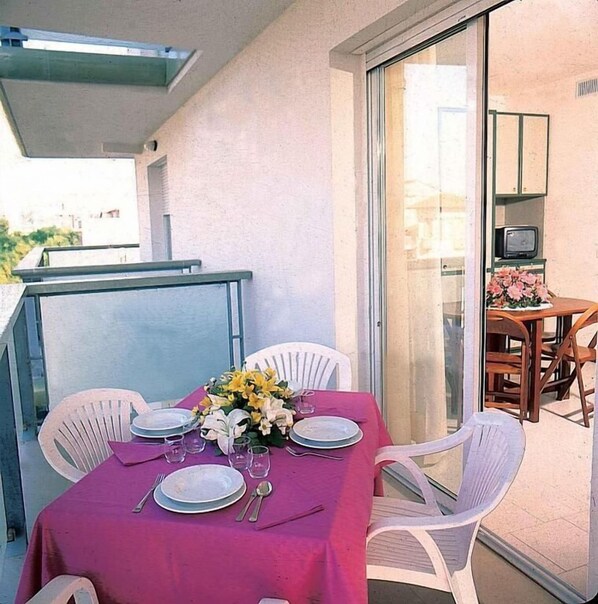 A dining area with a table set for four, white chairs, a pink tablecloth, and a flower centerpiece. - Residence Hotel Club House (Cattolica)