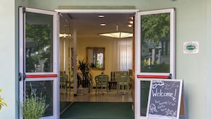 A hotel entrance with a green mat, a welcome sign, and a mirror. - Residence Hotel Club House (Cattolica)