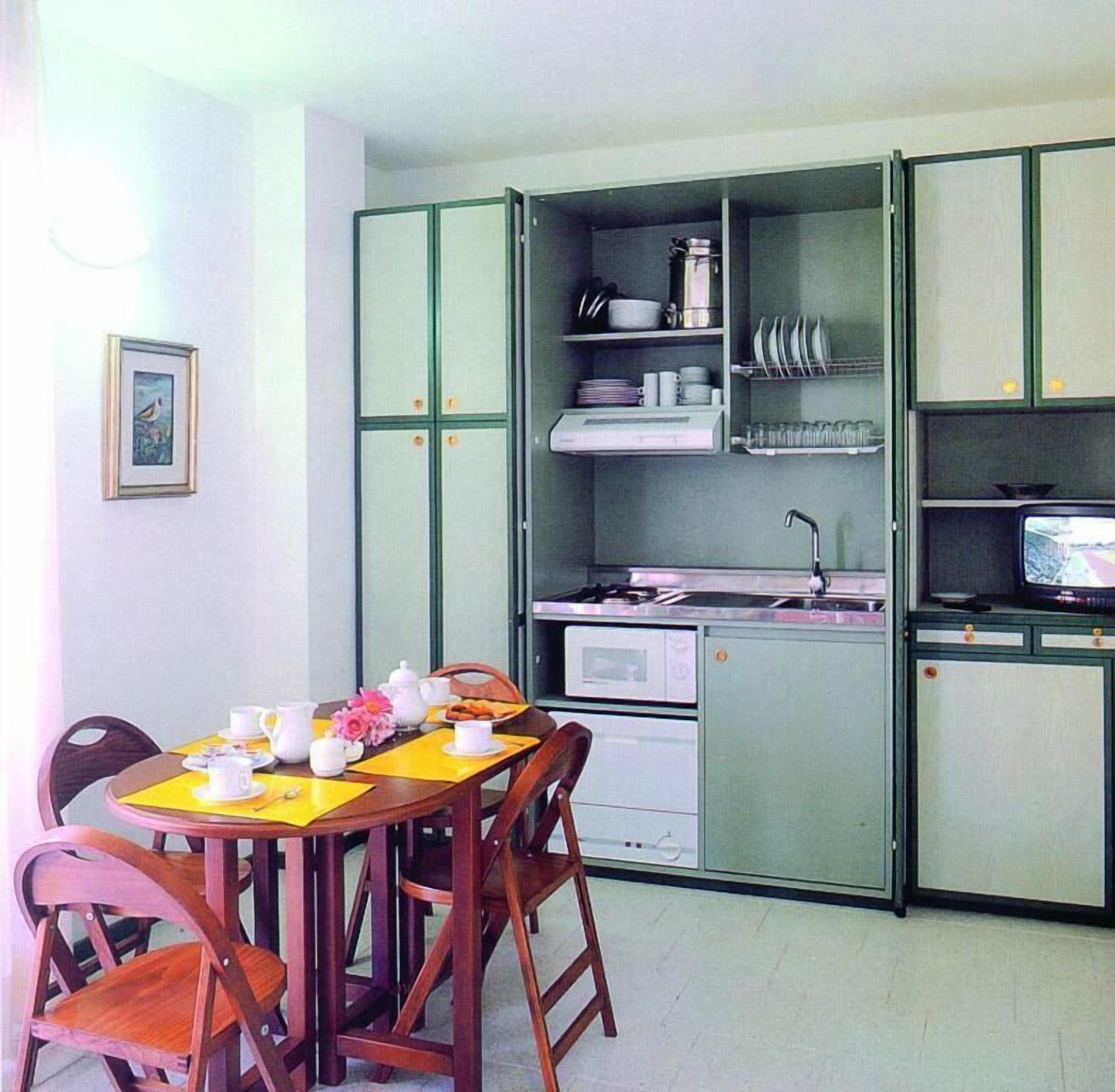A compact kitchen with a dining table set for two, a microwave, and a small TV.