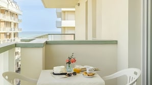 A balcony with a table set for breakfast, a vase with flowers, and a view of the sea. - Residence Hotel Club House (Cattolica)
