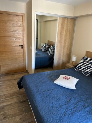 A bedroom with a bed, a wooden door, a mirror, and a nightstand. - Luxury apartment on the port of Bonifacio (Bonifacio)