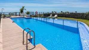 A clear blue swimming pool with a wooden deck, lounge chairs, and a stone wall in the background. - 7 - Bright house with private plunge pool (Mijas)