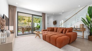 A modern living room with a sectional sofa, a dining area with a table and chairs, and a large sliding glass door leading to an outdoor patio. - 7 - Bright house with private plunge pool (Mijas)