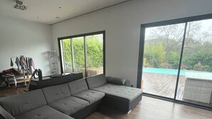 Una sala de estar moderna con un sofá seccional, un ventanal que da a una piscina y un gran ventanal.