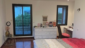 Un dormitorio con cama, cómoda, escritorio y vistas a través de puertas correderas.
