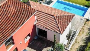 Una casa moderna con techo rojo, piscina y jardín.