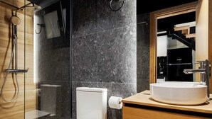 Een moderne badkamer met een douchecabine van glas, een toilet en een wastafel met spiegel erboven.