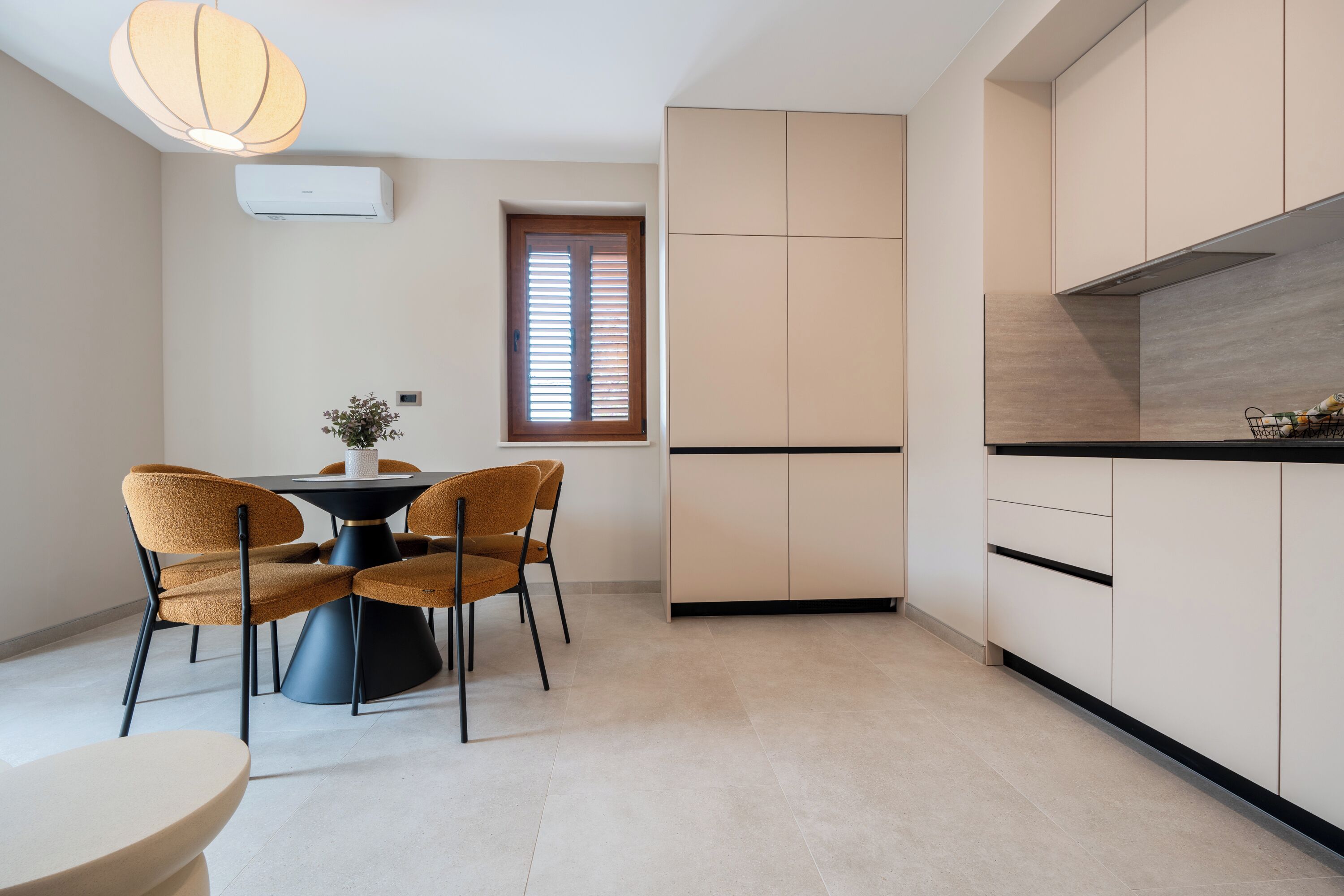 A modern kitchen with white cabinets, a black countertop, and a dining area with a round table and four chairs.