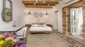 Ein Schlafzimmer mit Bett, Nachttischen, Schreibtisch, Spiegel und einer Steinwand.