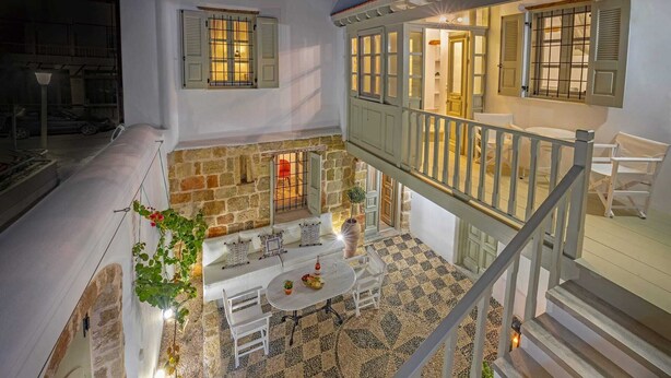 Ein mehrstöckiger Innenraum mit Steinwand, Balkon und Essbereich mit Tisch und Stühlen.