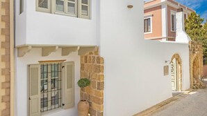 Ein zweistöckiges Gebäude mit weißer Fassade, einer Steinmauer und einem kleinen Blumentopf.