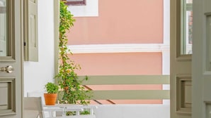 A balcony with a white chair, a potted plant, and a wall-mounted lamp. - Amarada Nostalgia City Suite, Αpartment (Rhodes)
