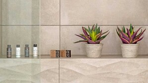 Ein Badezimmer mit gefliesten Wänden, zwei Topfpflanzen und einem Ablagefach mit Toilettenartikeln.