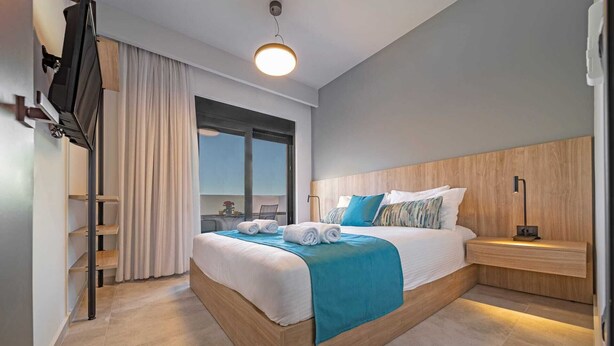 Een moderne hotelkamer met een groot bed, een nachtkastje, een televisie en een raam.