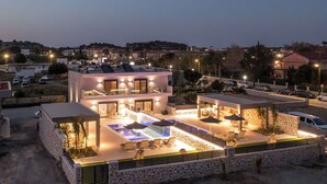 Une maison moderne à deux étages, dotée d’une piscine, d’un espace extérieur aménagé et d’une façade en pierre.