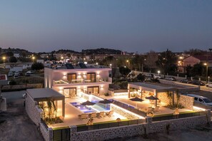 A modern two-story house with a swimming pool, outdoor seating, and a stone facade. - Calma Luxury Villa (T), Villa (Rhodes)