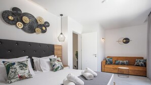 Une chambre à coucher moderne avec un lit, un canapé et une œuvre d’art murale.