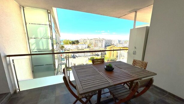 Ein Balkon mit Tisch und Stühlen und Blick auf die Stadt, sowie eine Glastür.