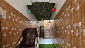 A spa room with a massage chair, artificial grass flooring, and patterned walls.