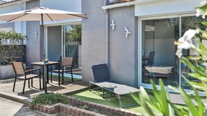 Un patio con tavolo, sedie e una poltrona relax.