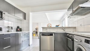 Una cucina moderna con elettrodomestici in acciaio inossidabile, lavastoviglie e lavatrice.