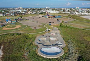 An aerial view of a park with a baseball field, a skate park, and a swimming pool. - 2-Min Walk to Beach + Boardwalk + Golf Cart Zone | Serenity by the Sea (Port Aransas)