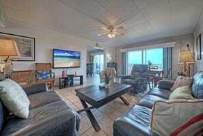 Ein Wohnzimmer mit Ledersofas, einem Couchtisch, einem Fernseher und einem Deckenventilator.