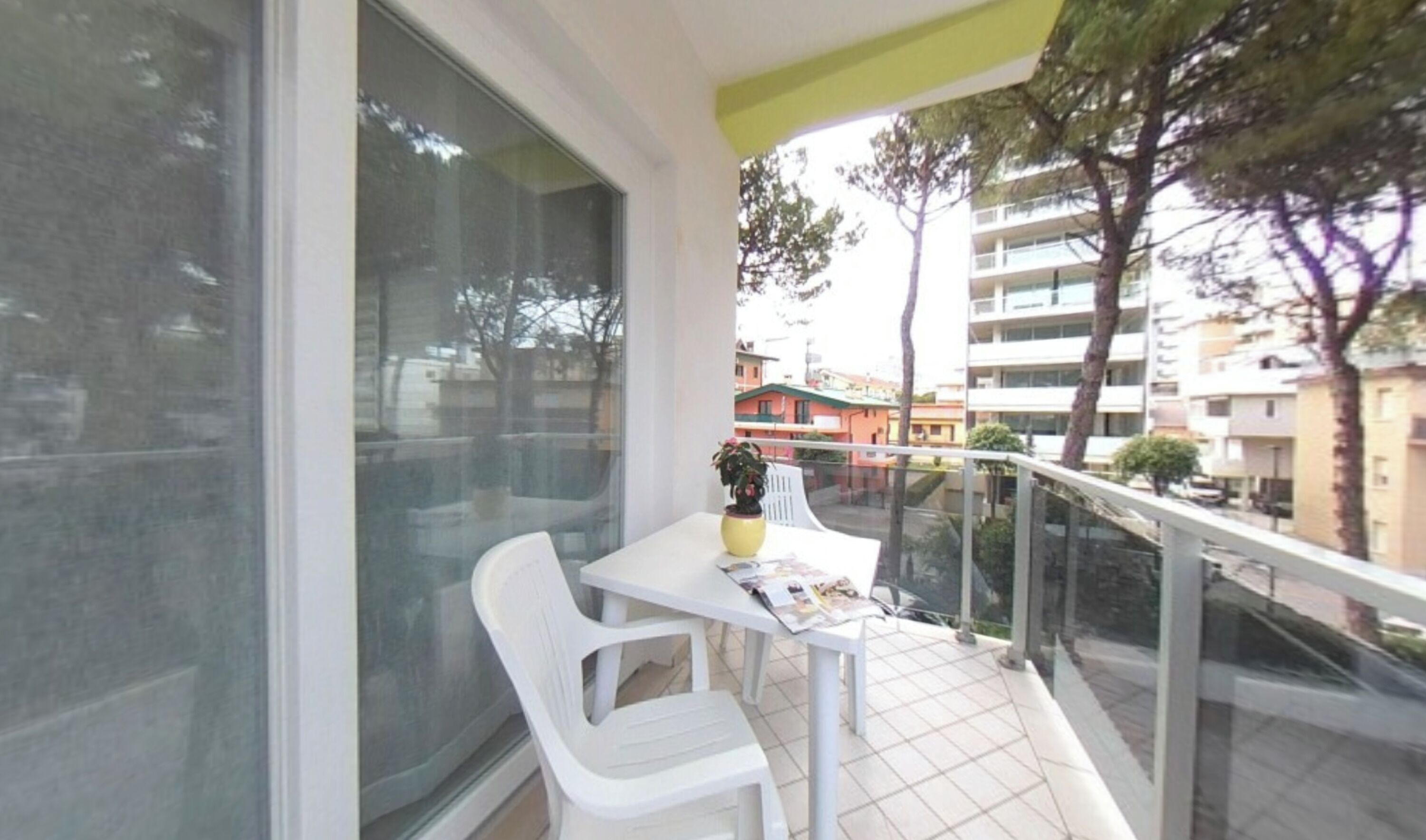 Varanda com mesa, cadeiras, um vaso de planta e vista para edifícios.