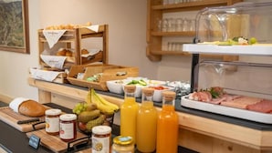A breakfast buffet with bread, fruits, juices, and meats. - Hofers Herzstück (Hinterglemm)
