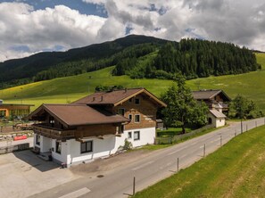 Un paysage rural avec deux maisons en bois, une route asphaltée et une colline verdoyante.