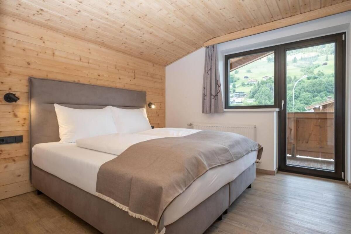 A wooden-paneled room with a bed, a window with a view, and a radiator.
