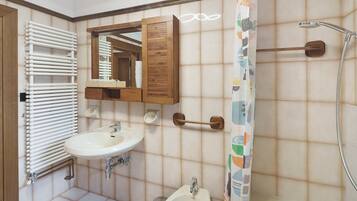 A bathroom with a white sink, a wooden cabinet, a mirror, a shower, and a toilet.